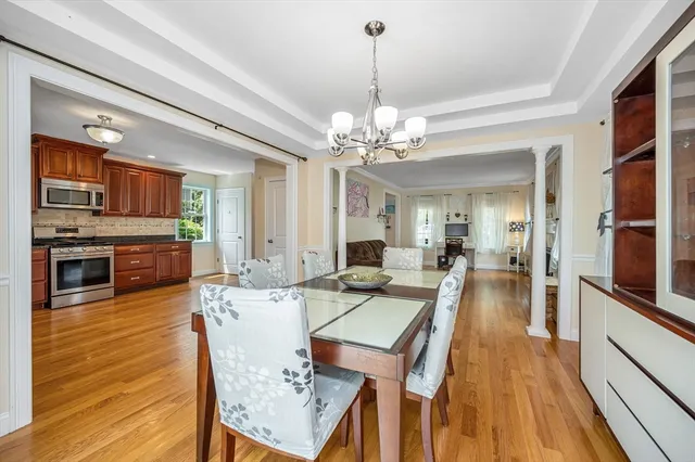 a view of a dining room and livingroom with furniture wooden floor a chandelier