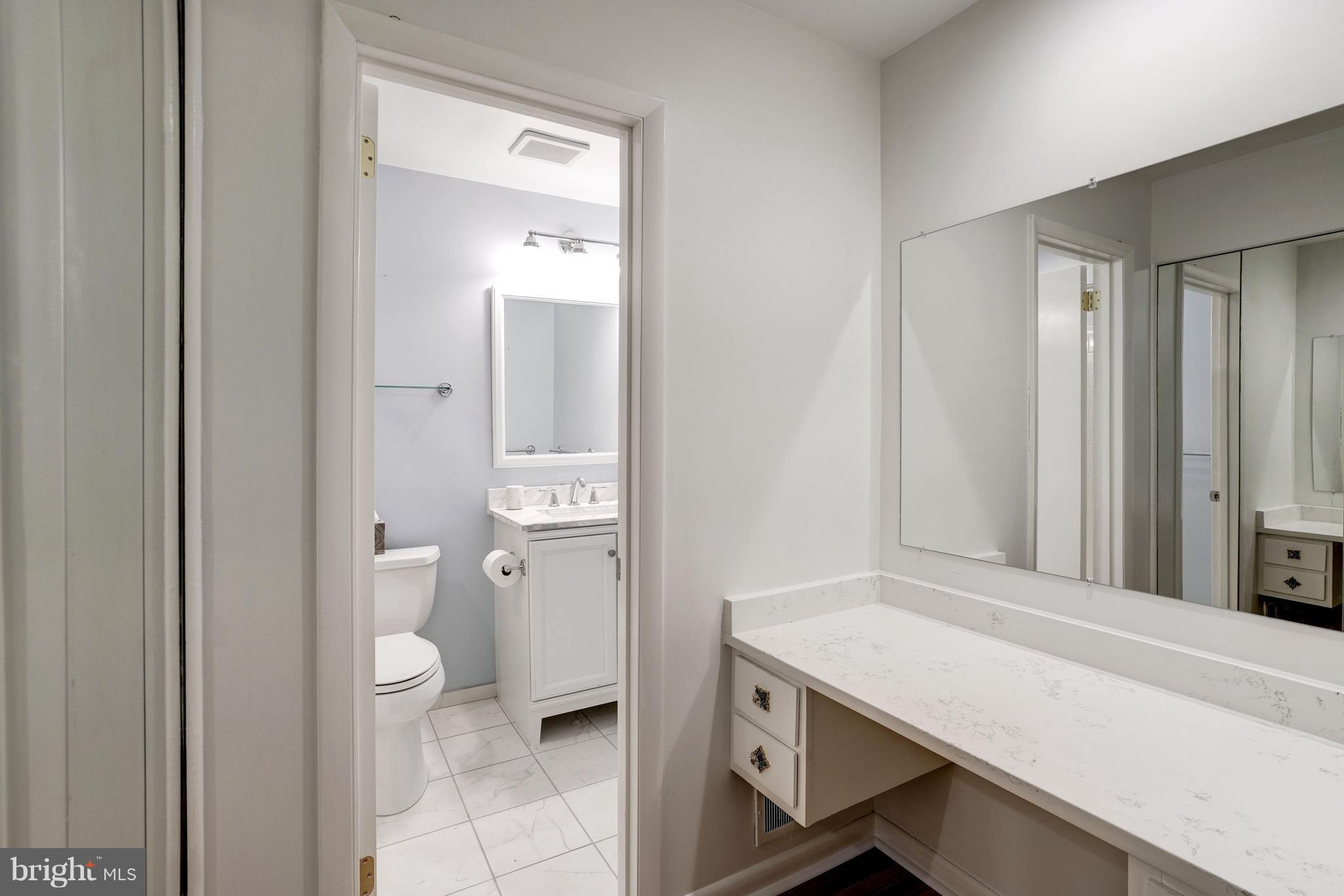 11302 Fairway Drive Reston, VA 20190 - Photo 15 of 30 a bathroom with a granite countertop sink a toilet and a mirror