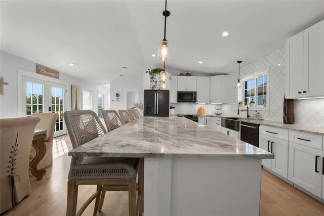 a view of a dining room and livingroom furniture a chandelier and kitchen view