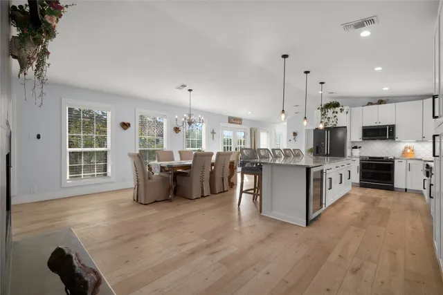 a kitchen with kitchen island granite countertop a sink a center island a stove and a chandelier