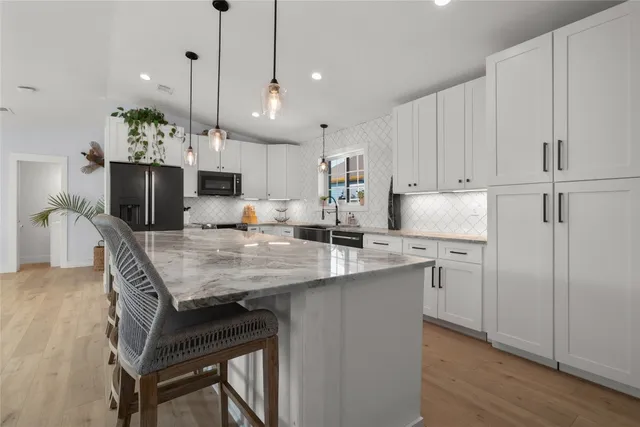 a large kitchen with kitchen island a stove a sink a center island and couches