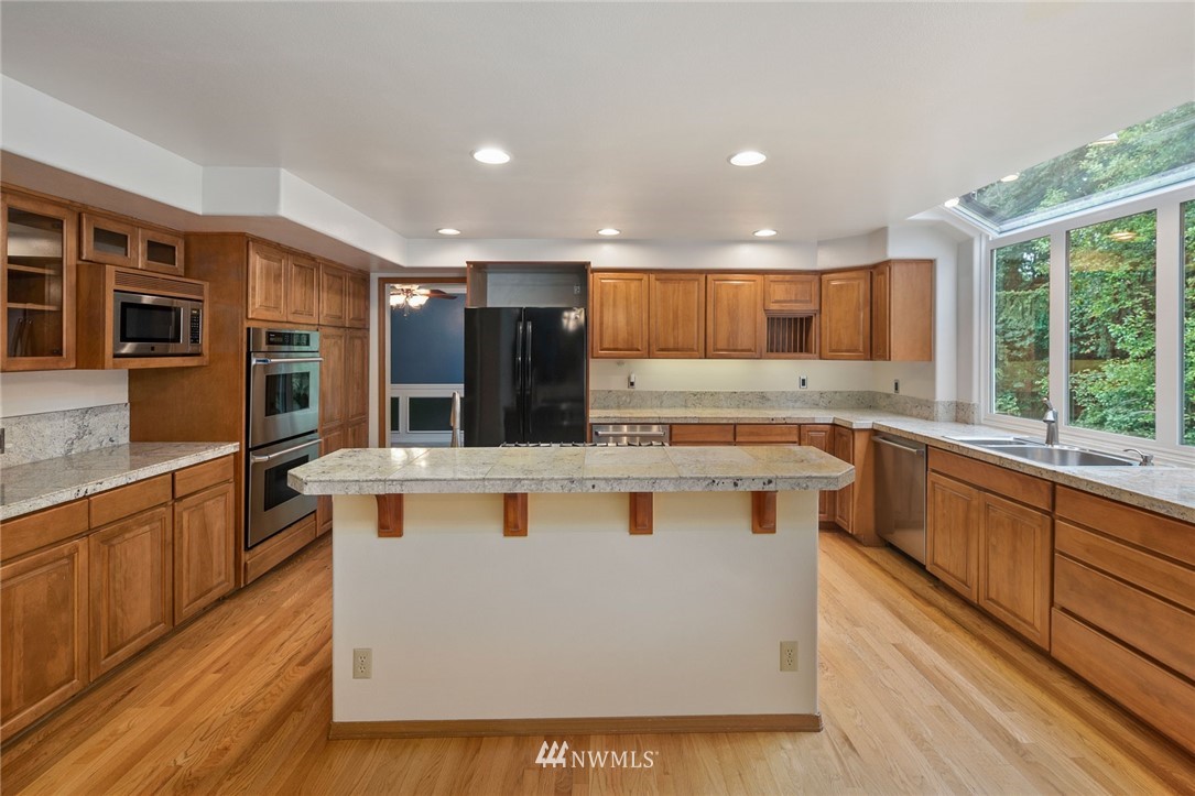 16045 Southeast 149th Street Renton, WA 98059 - Photo 12 of 39 a kitchen with kitchen island granite countertop wooden floors and stainless steel appliances