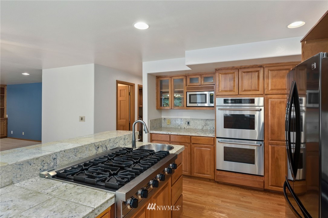 16045 Southeast 149th Street Renton, WA 98059 - Photo 16 of 39 a kitchen with stainless steel appliances granite countertop a stove a sink and a refrigerator