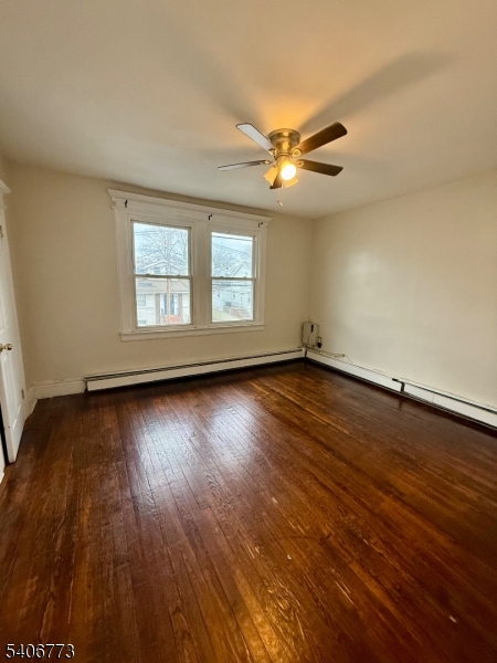 an empty room with wooden floor chandelier fan and windows