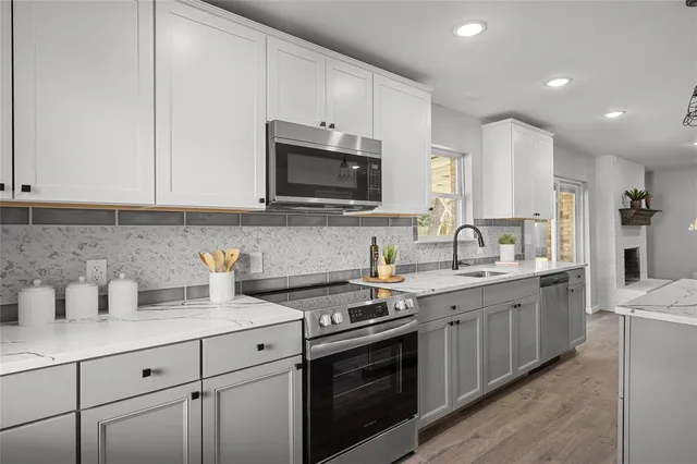 a kitchen with stainless steel appliances granite countertop a sink dishwasher stove and white cabinets with wooden floor