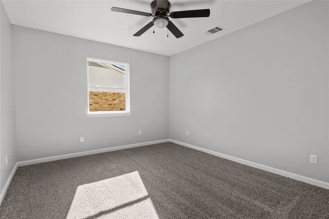 an empty room with a window and a ceiling fan
