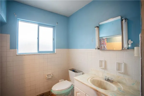 a bathroom with a toilet a sink a mirror and a window