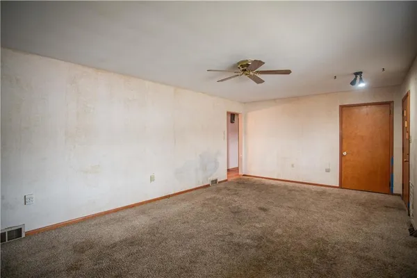 an empty room with a ceiling fan and carpet