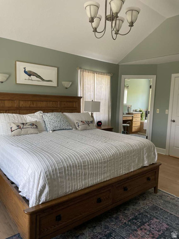 7030 West 2100 North Mendon, UT 84325 - Photo 35 of 67 Spacious bedroom featuring vaulted ceilings, a chandelier fixture, light-colored walls, wood-finish flooring, and a doorway opening to an additional room