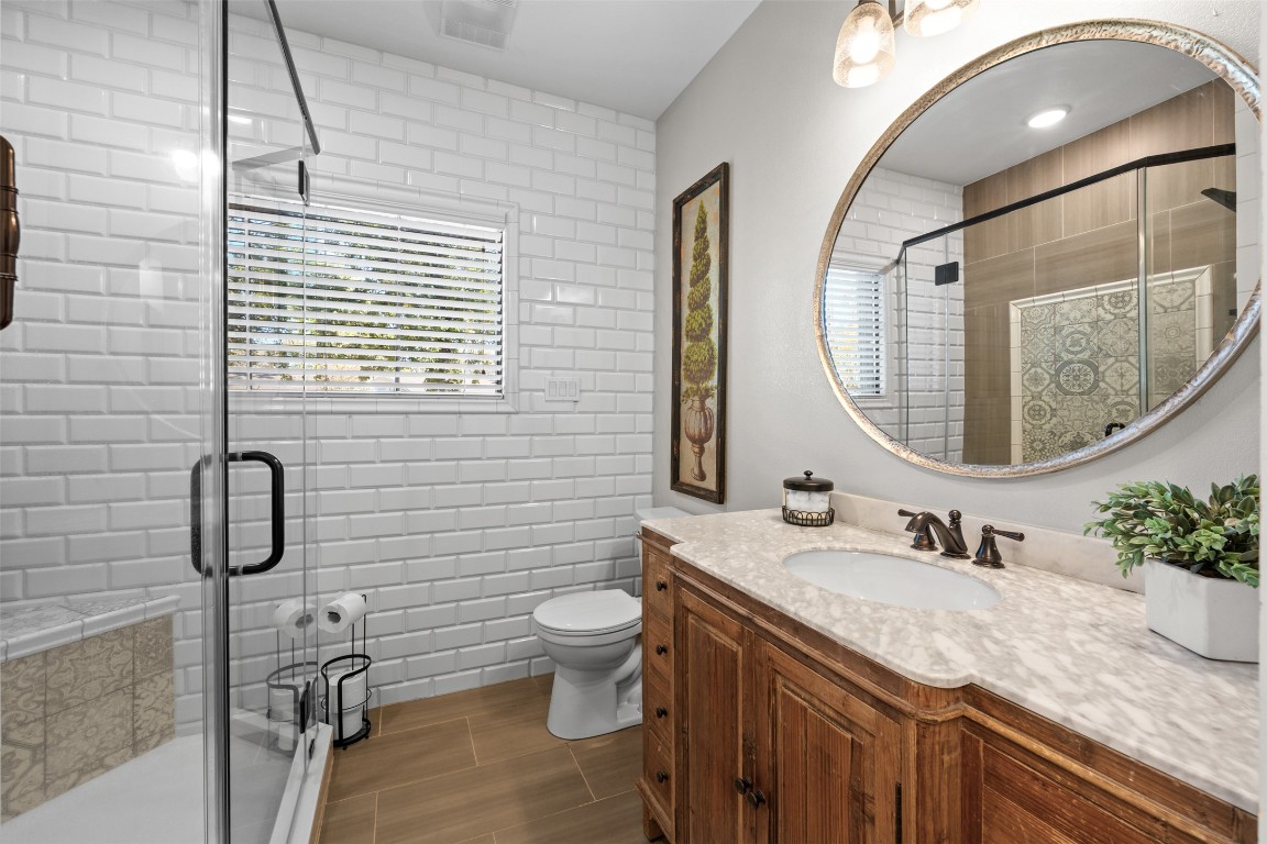 1005 East 14th Street Cameron, TX 76520 - Photo 27 of 40 a bathroom with a granite countertop sink a toilet and a mirror