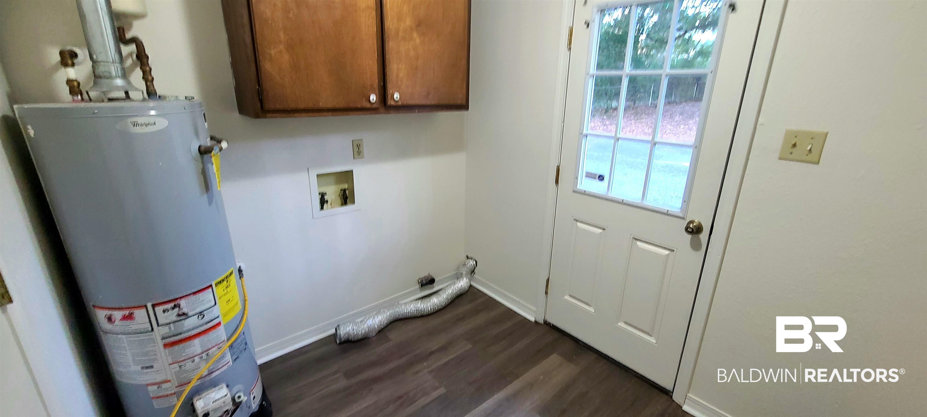 5305 Wilhelm Drive Mobile, AL 36618 - Photo 13 of 16 Clothes washing area featuring water heater, dark hardwood / wood-style floors, a wealth of natural light, and cabinets