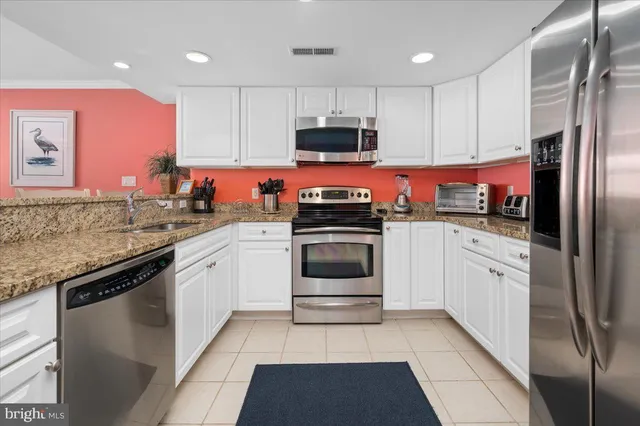 a kitchen with granite countertop a refrigerator sink and microwave