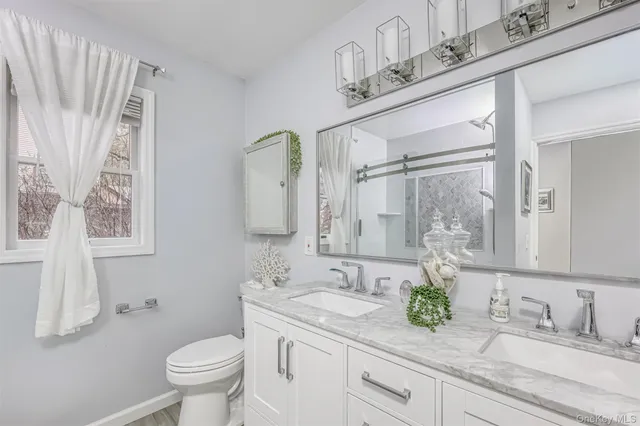 a bathroom with a granite countertop sink a toilet and a mirror