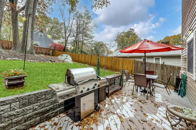 a patio with a table and chairs under an umbrella with a barbeque
