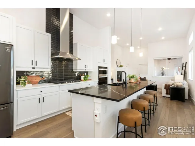 a kitchen with stainless steel appliances granite countertop a sink a stove and a wooden floors