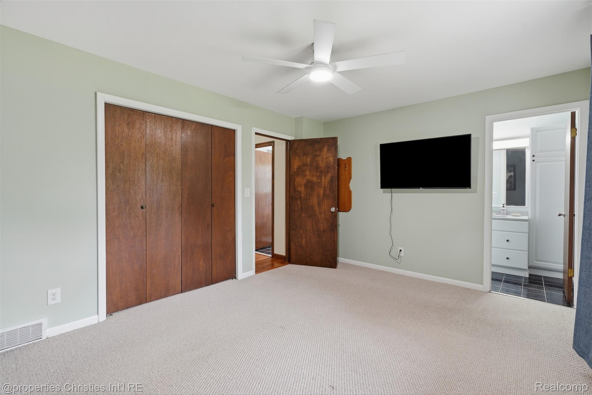 4030 Textile Road Ypsilanti, MI 48197 - Photo 21 of 58 Plush carpeting, wood-paneled bi-fold closet doors, a ceiling fan with integrated lighting, and a wall-mounted television