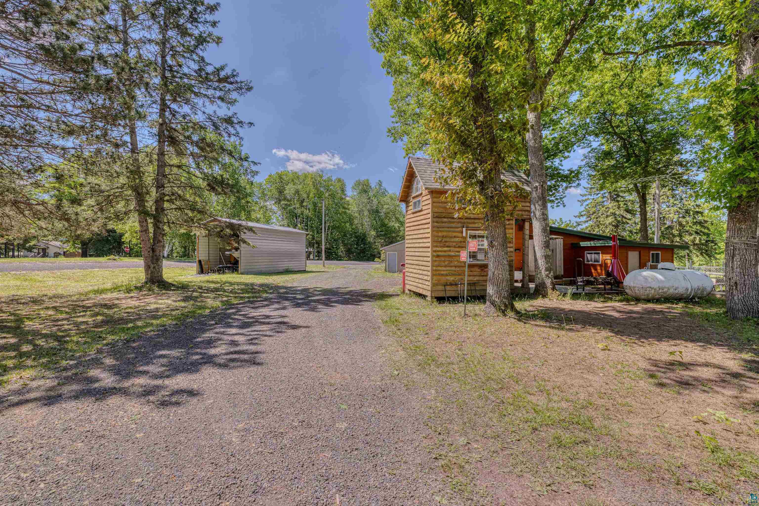 66075 Rooster Road Iron River, WI 54847 - Photo 36 of 52 Gravel driveway extending to a rustic-style home with a log-siding exterior and a covered front porch