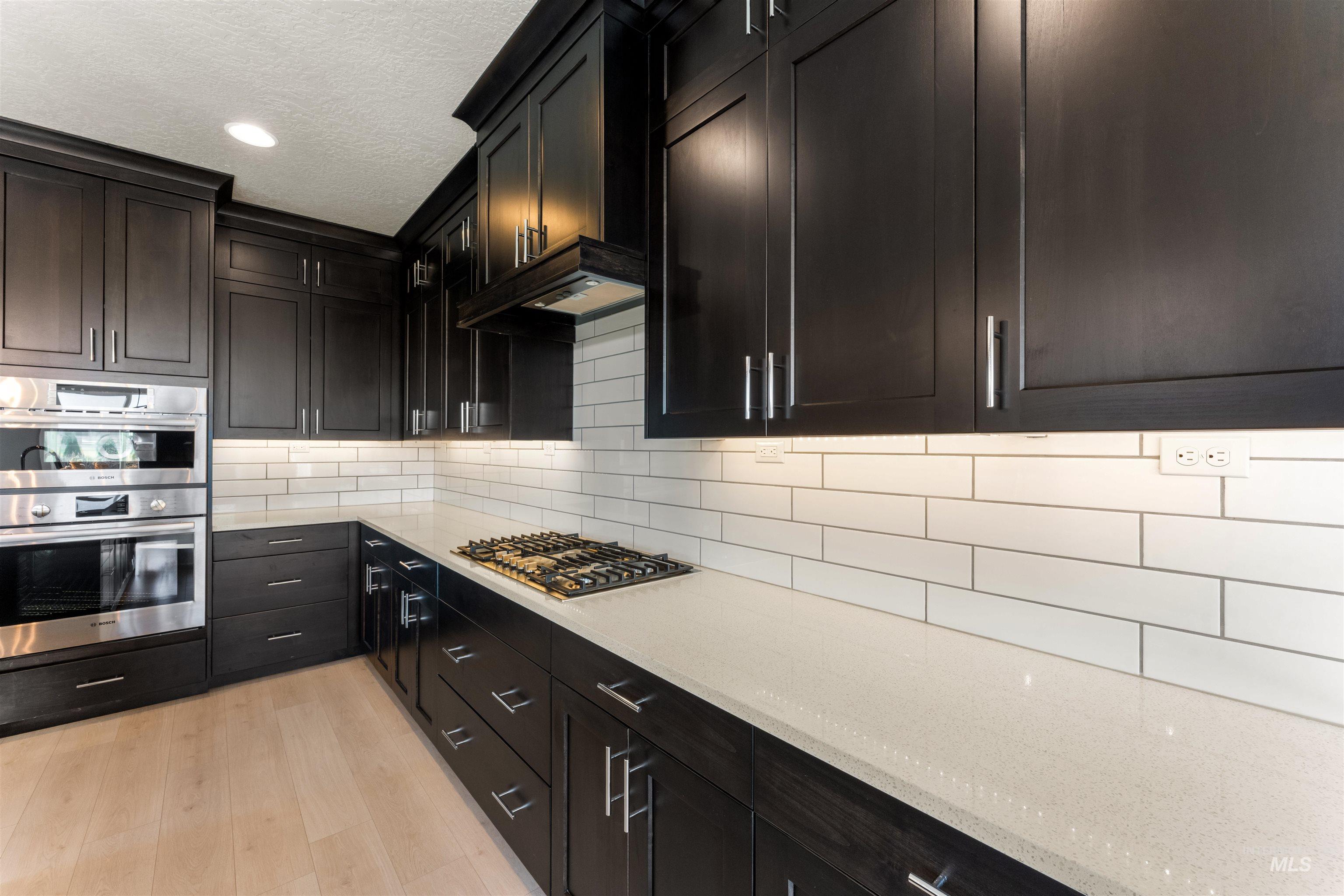 8097 Tandy Cove Street Middleton, ID 83644 - Photo 11 of 37 Kitchen with light stone countertops, stainless steel appliances, light wood finished floors, tasteful backsplash, and recessed lighting