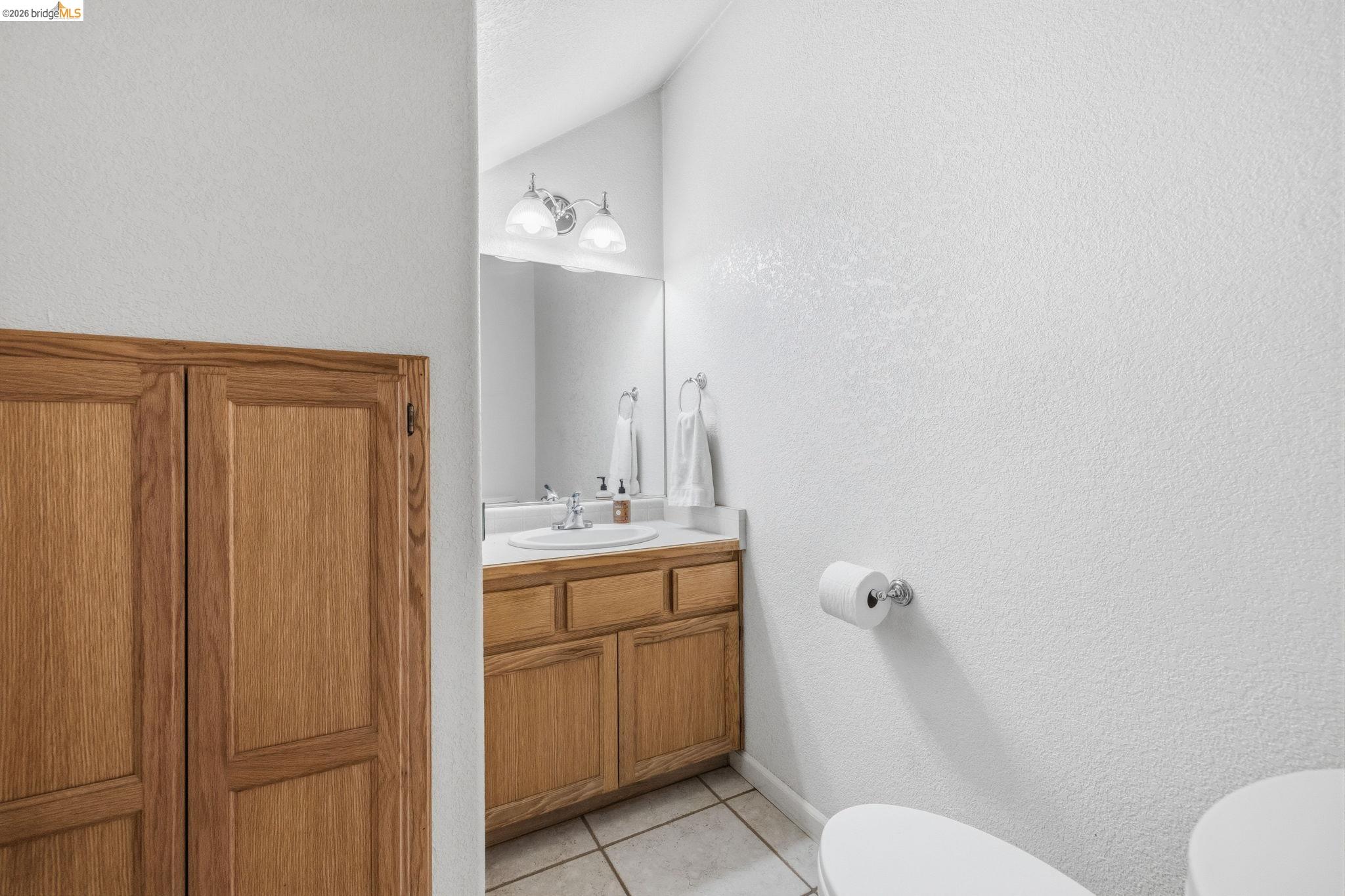 18450 Lambert Lake Road Sonora, CA 95370 - Photo 57 of 87 Bathroom vanity featuring wood-finish cabinetry, a white countertop, and an integrated sink with a chrome faucet