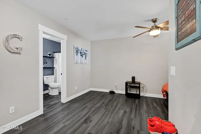 a view of empty room with wooden floor and fan