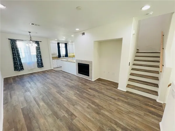 an empty room with wooden floor and a kitchen