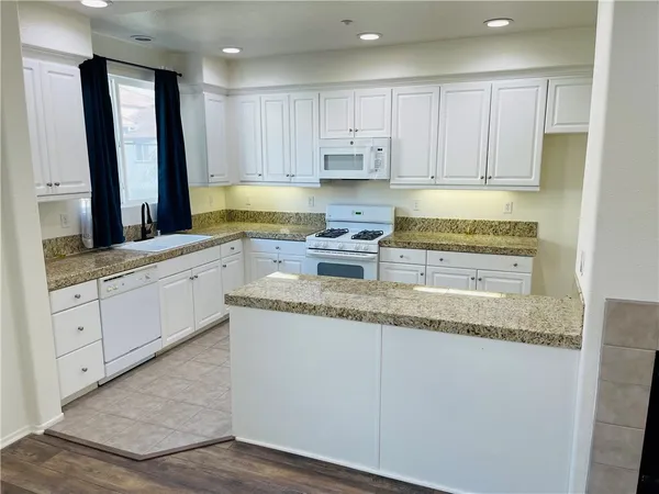 a kitchen with granite countertop white cabinets white appliances and granite countertops