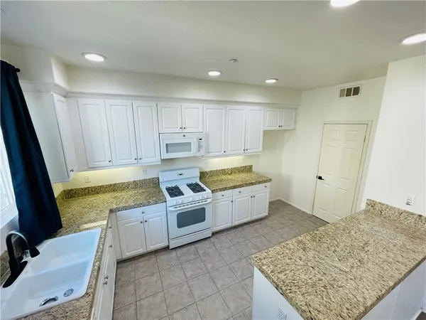 a large kitchen with stainless steel appliances granite countertop a sink and cabinets