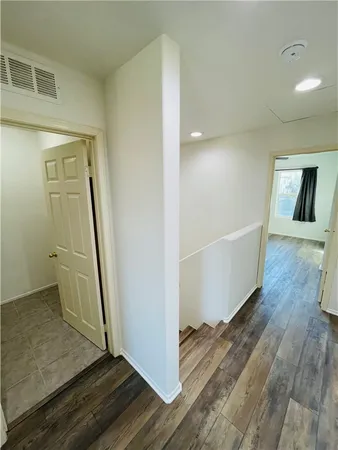 a view of a hallway to rooms and wooden floor