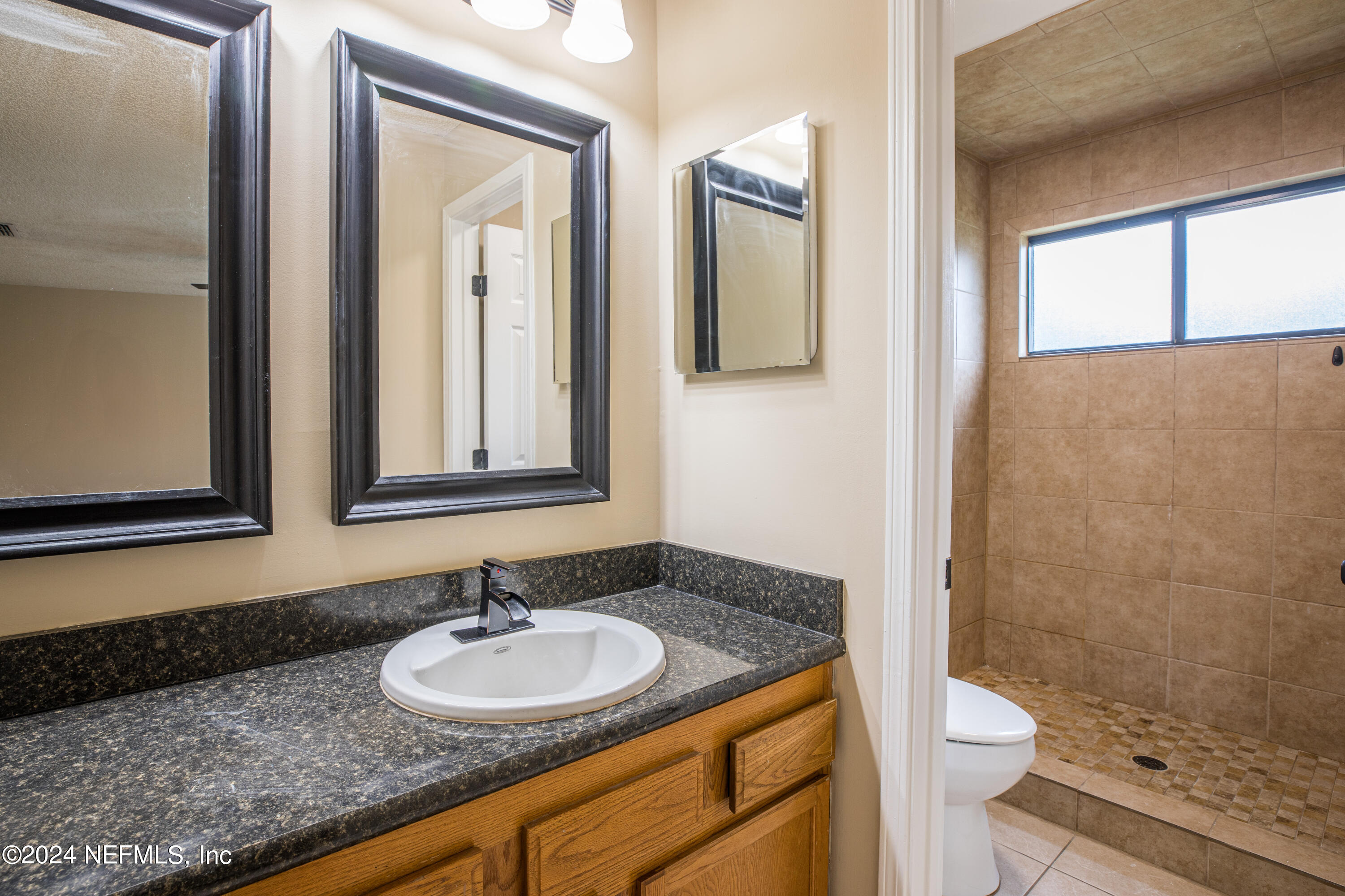 8691 Hammond Forest Drive Jacksonville, FL 32221 - Photo 21 of 28 a bathroom with a granite countertop sink toilet a mirror and shower