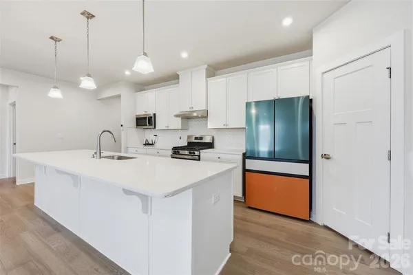 a kitchen with stainless steel appliances a sink a refrigerator a center island a stove and cabinets