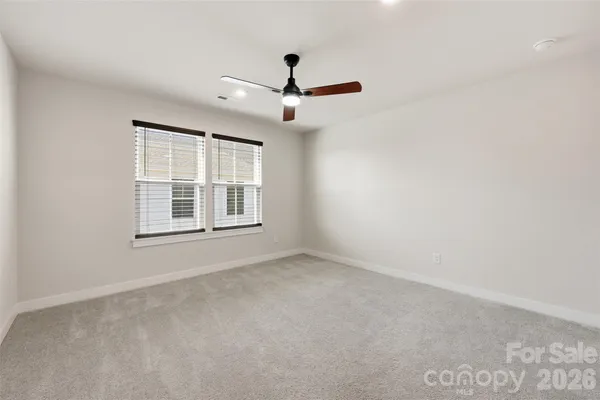 an empty room with windows and ceiling fan