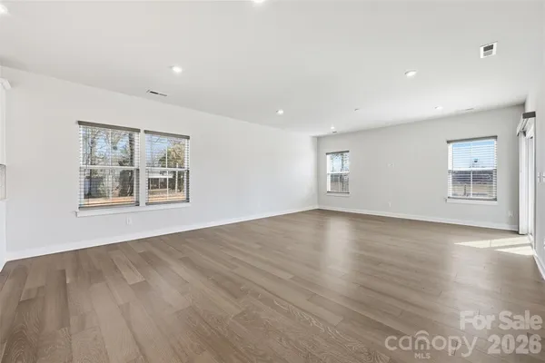 a view of an empty room with window and wooden floor