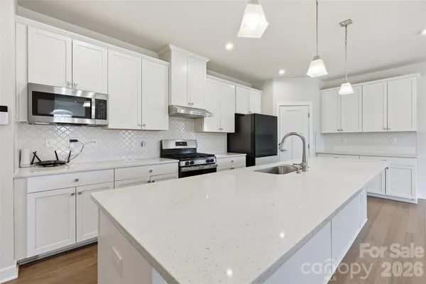 a kitchen with stainless steel appliances a sink a stove a microwave a center island and cabinets