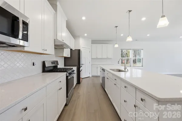 a large kitchen with stainless steel appliances lots of counter space sink refrigerator and cabinets