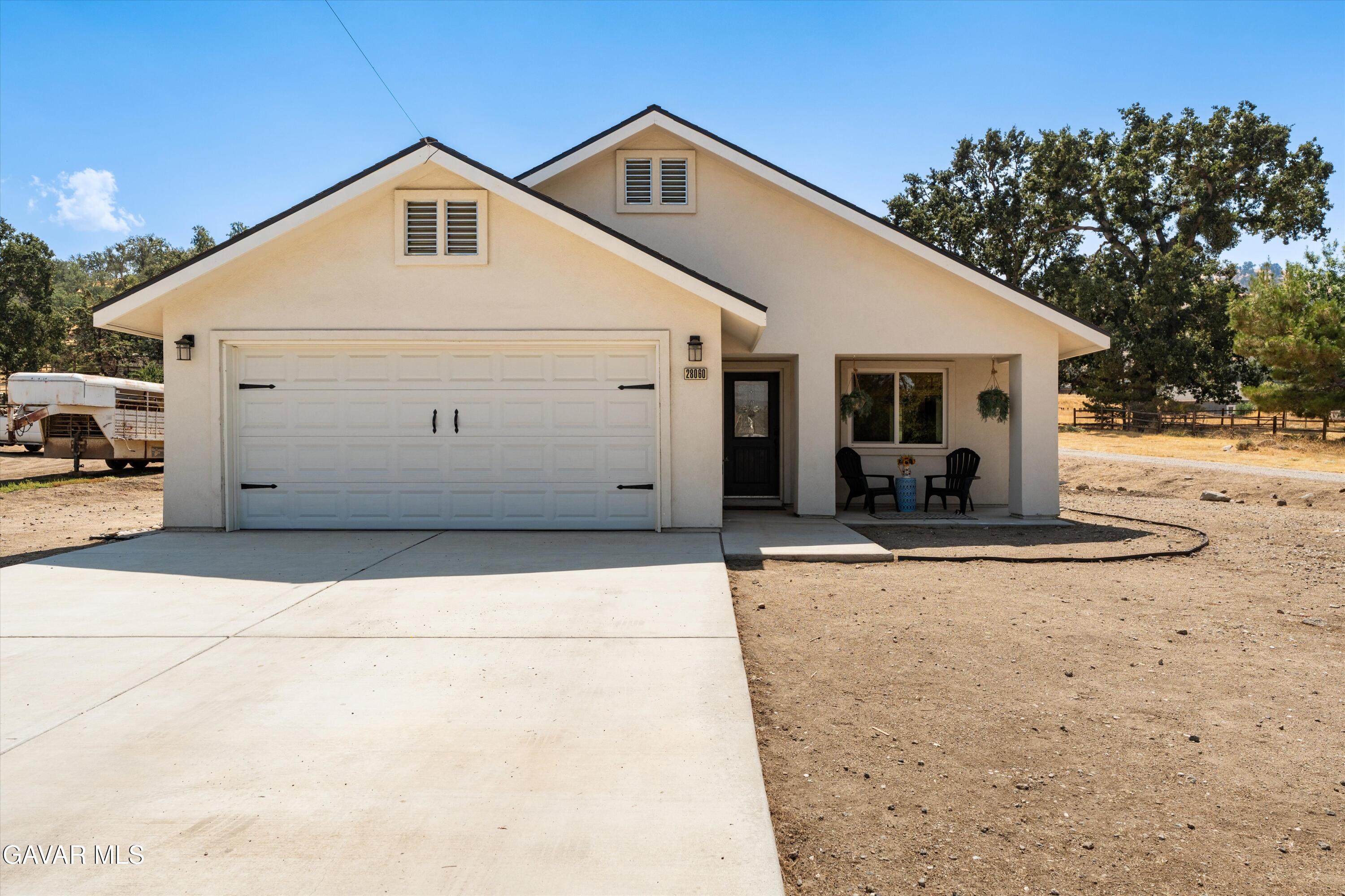 28060 Preakness Drive Tehachapi, CA 93561 - Photo 2 of 26 a view of a white house with large outdoor space and a car parked in front of it
