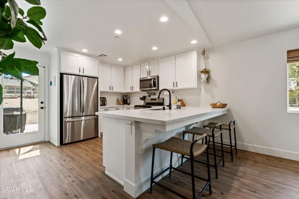 a kitchen with stainless steel appliances granite countertop a refrigerator a sink a stove a microwave and a refrigerator