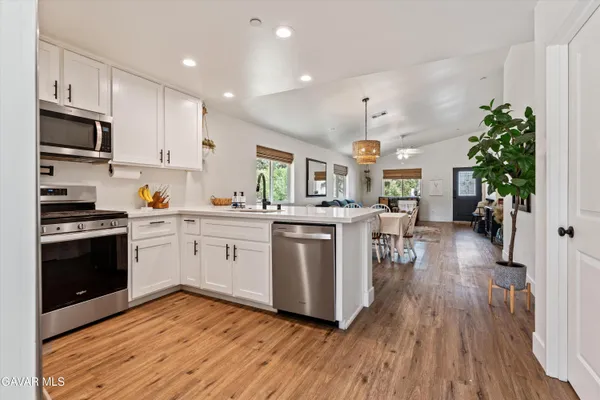 a kitchen with granite countertop a refrigerator stove and wooden floor