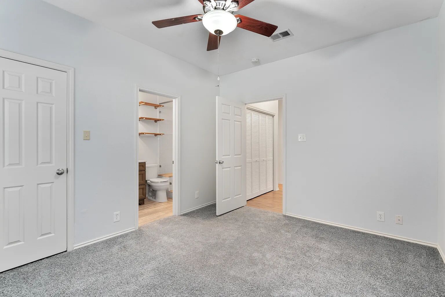 11970 Jollyville Road, Unit 202 Austin, TX 78759 - Photo 12 of 25 A comfortable bedroom with soft grey carpet, complete with a functional ceiling fan for optimal air circulation.