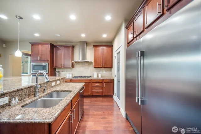 a kitchen with stainless steel appliances granite countertop a sink a stove and a refrigerator