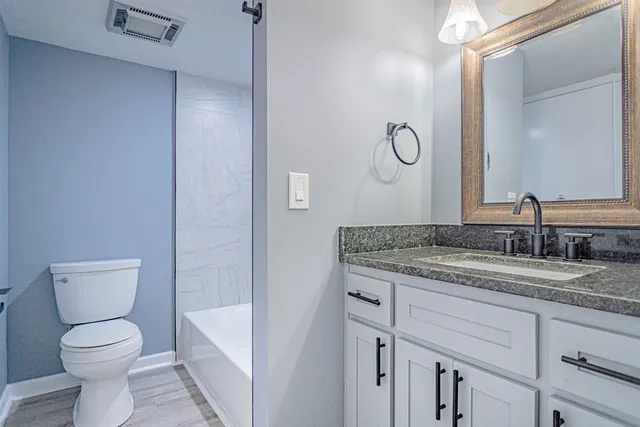 a bathroom with a granite countertop toilet sink and mirror
