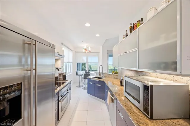 a kitchen with stainless steel appliances granite countertop a refrigerator a stove and a sink with wooden floor