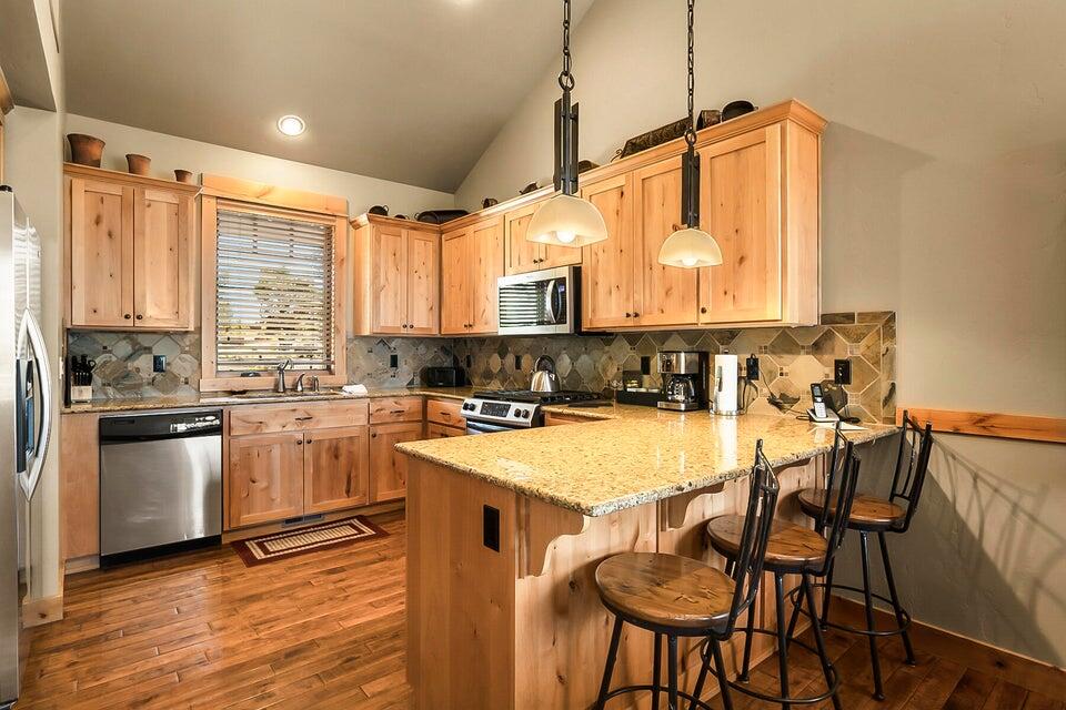 16845 South W Brasada Ranch Road, Unit 23 Powell Butte, OR 97753 - Photo 15 of 47 a kitchen with stainless steel appliances granite countertop a stove a sink dishwasher and a refrigerator with wooden floor