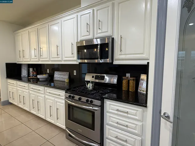 a kitchen with stainless steel appliances granite countertop white cabinets and a stove a refrigerator with white cabinets