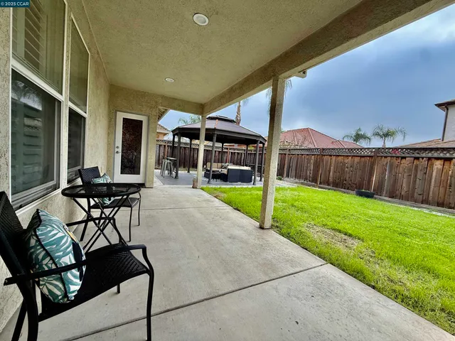 a view of a backyard with table and chairs and a barbeque