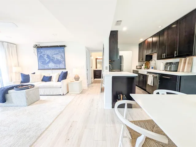 a living room with furniture a flat screen tv and kitchen view