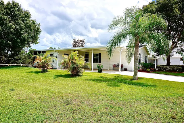 a view of a house with a big yard and large trees