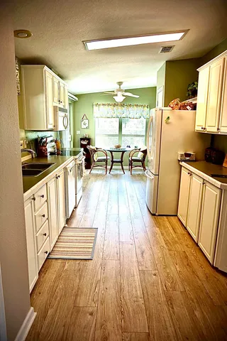 a kitchen with sink a refrigerator and wooden floor