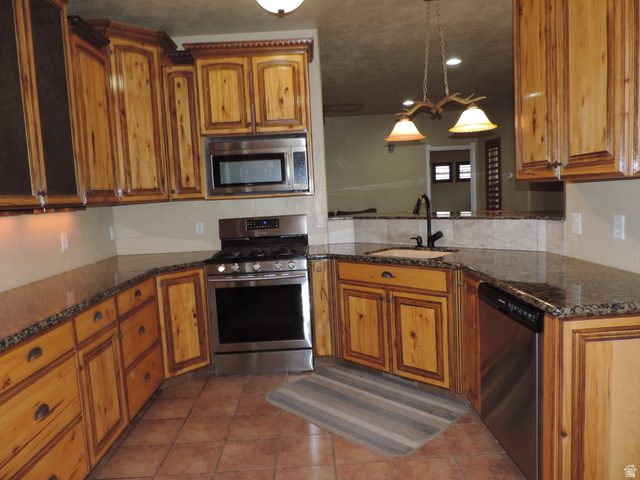 140 North 200 E Street Glenwood, UT 84730 - Photo 9 of 54 Kitchen with stainless steel appliances, dark stone counters, wood finish cabinetry, dark tile patterned flooring, and decorative light fixtures