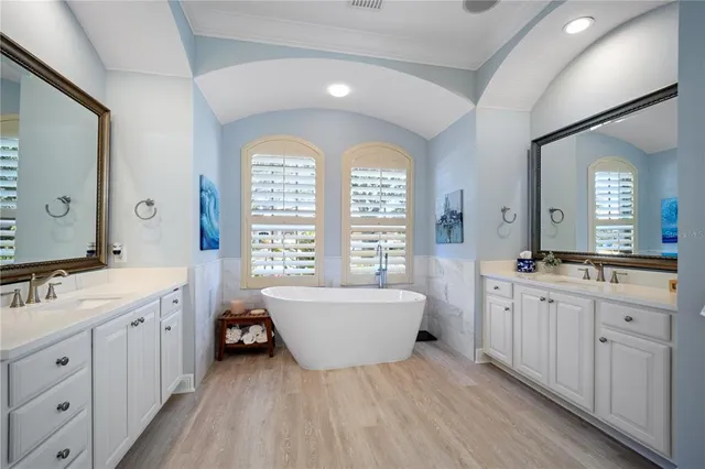 a spacious bathroom with double vanity a mirror a bathtub and window