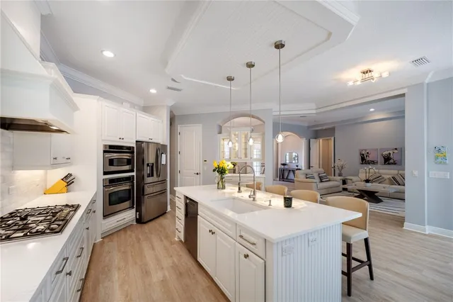 a large white kitchen with a refrigerator a stove a dining table and chairs with wooden floor